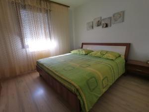 a bedroom with a bed with a green comforter and a window at Apartment Lošč - Podbela in Breginj +36 photos