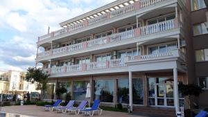 a hotel with blue chairs in front of a building at Студио Сънрайз А28, Лозенец in Lozenets