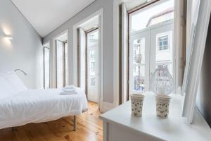 Habitación blanca con cama y ventana en LovelyStay - Porto Windows with AC by central station, en Oporto