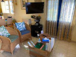 sala de estar con sillas de mimbre y TV de pantalla plana en Casa Azul, en Guía de Isora