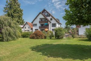 ein großes weißes Haus mit einem Rasenhof in der Unterkunft Gästehaus Heinemann - Eg5 in Langenargen