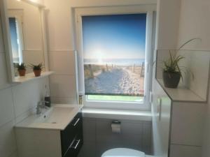 a bathroom with a window with a view of a beach at Ferienhaus Scandia am See in Warnitz