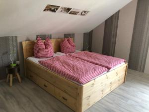 a bedroom with a wooden bed with pink sheets and pillows at Carolinger Hüttendorf in Weyer