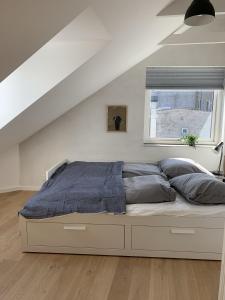 a bed in a white room with a window at aday - Penthouse 3 bedroom - Heart of Aalborg in Aalborg