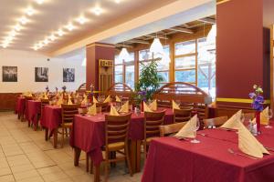 a dining room with tables and chairs with red tablecloths at Hotel Skalní Mlýn in Blansko