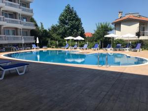 a large swimming pool with chairs and umbrellas at Студио Сънрайз А28, Лозенец in Lozenets
