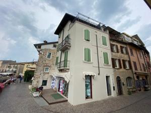 a white building with green shutters on a street at Castello Mavino in Sirmione