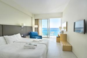 una habitación de hotel con 2 camas y una silla azul en Pernera Beach Hotel en Protaras