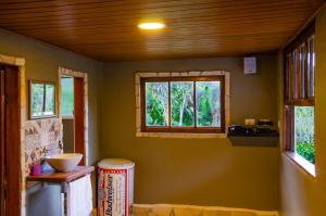 a kitchen with green walls and windows and a counter at Pousada Refúgio das Aves in Visconde De Maua