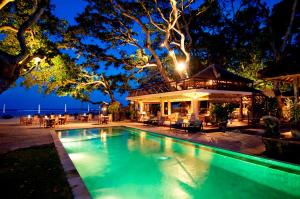 a swimming pool in front of a house at night at Tandjung Sari Hotel in Sanur