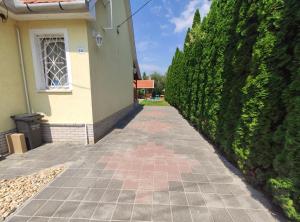a walkway in front of a house with a hedge at Apollo Vendégház in Bogács