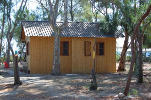 a small yellow house in the middle of trees at MIMOSA CAMPING in Isca sullo Ionio