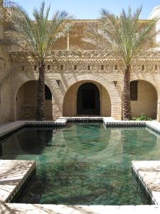 a swimming pool with palm trees in a building at DAR NEJMA in Tozeur