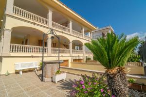 a large building with a bench and a palm tree at Llepol in Port d'Alcudia