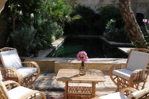 un patio avec des chaises, une table et une fontaine dans l'établissement DAR NEJMA, à Tozeur