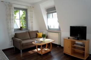 - un salon avec un canapé, une télévision et une table dans l'établissement Weingut Martin Blass, à Erlabrunn