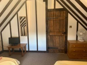 a bedroom with a wooden door and a desk with a television at Rose Cottage in Rye