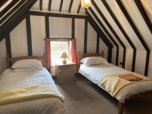 two beds in a attic room with a window at Rose Cottage in Rye