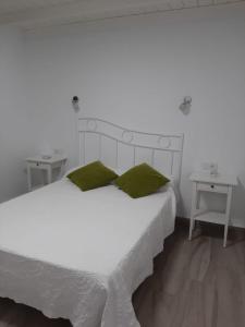 プエルト・デル・カルメンにあるBungalow La Marisma Puerto Del Carmenの白いベッド(緑の枕、テーブル2台付)