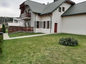 uma grande casa branca com um jardim de relva em NA KOŃCU ŚWIATA em Muszyna