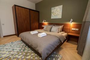 1 dormitorio con 1 cama con 2 toallas en Roze Brīvzemnieka Apartments en Liepāja