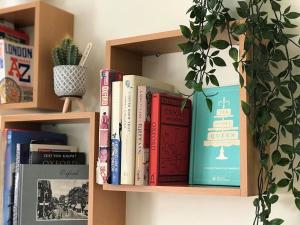 a book shelf filled with books and a potted plant at A'nB Oxford LUX 2-Bedroom plus private parking 5-STAR Central OX1 in Oxford