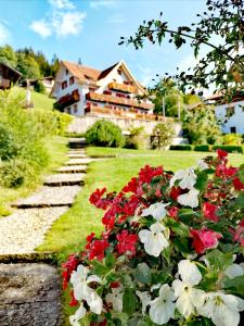 un jardín con flores rojas y blancas frente a una casa en Hotel Sterne en Beatenberg