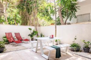 a white table and chairs on a patio with trees at Mr. Montana - By TLV2GO in Tel Aviv