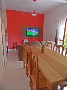 a dining room with a wooden table and a tv at Casa Vila Dom Pedro in Paraty +1 photo