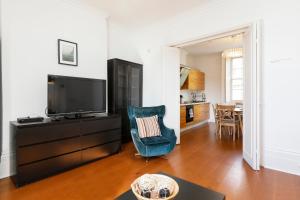 a living room with a television and a blue chair at Fantastic Stays at Camden in London