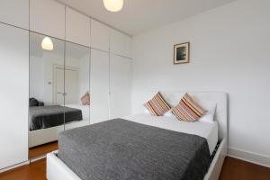 a white bedroom with a bed and a mirror at Fantastic Stays at Camden in London