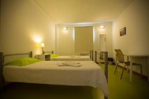 a hotel room with a bed, chair, and nightstand at HI Castelo Branco - Pousada de Juventude in Castelo Branco