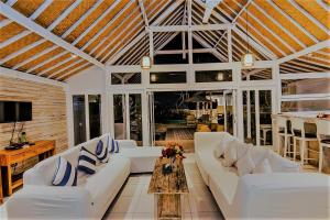 a living room with white furniture and a wooden ceiling at Villa Waru One in Nusa Lembongan