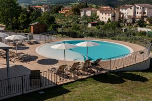 ein großer Pool mit Stühlen und Sonnenschirmen in der Unterkunft Il Torrino in Pomarance