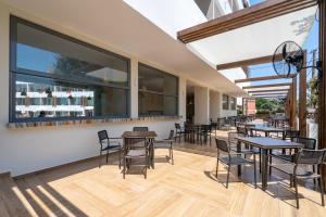 a patio area with tables, chairs, and tables with umbrellas at Castellum Suites - All Inclusive in Rhodes Town