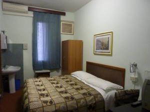 a bedroom with a bed and a sink and a window at Albergo Junior in Padova