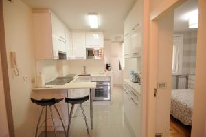 a kitchen with white cabinets and bar stools at Apartamento Vigo Centro con Garaje in Vigo