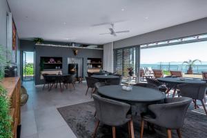 a dining room with tables and chairs and a view of the ocean at Romans Villa in Gansbaai