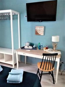 een bureau met een televisie aan een blauwe muur bij Only for two Giumbabulla in Ragusa
