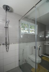 a bathroom with a toilet and a glass shower at Surfers Beach Self Catering Chalets in Takamaka
