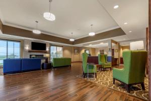 een kantoorlobby met groene stoelen en een tafel bij Comfort Suites in Grand Island