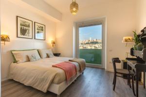 a bedroom with a bed and a desk and a window at Eleventh Floor Suites in Cagliari