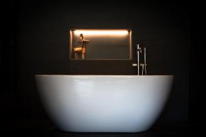 a white tub in a black bathroom with a mirror at Hotel Naudi Boutique Adults only in Soldeu