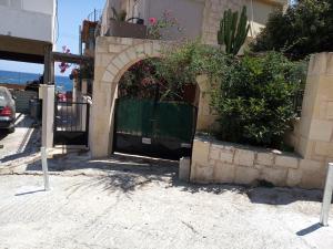 an entrance to a building with a gate and bushes at Buganvilla Sea View apts in Agia Pelagia