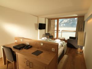 a bedroom with a bed and a desk and a room with a view at Seevilla Freiberg in Zell am See