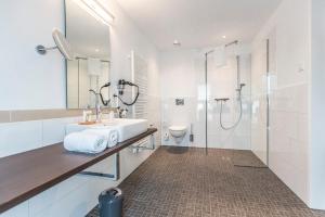 a white bathroom with a sink and a shower at Hotel Am Markt in Ennigerloh