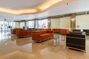 una sala de espera con mesas y sillas de cuero marrón en Hotel Roma, en Lisboa