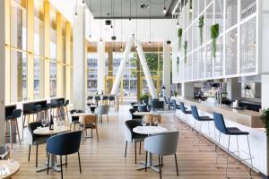 a restaurant with tables and chairs and windows at Holiday Inn Express Amsterdam - North Riverside by IHG in Amsterdam