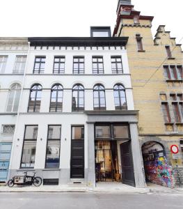 ein weißes Gebäude mit schwarzen Türen auf einer Straße in der Unterkunft MAISON12 - Design apartments with terrace and view over Ghent towers in Gent