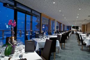 a dining room with white tables and chairs and windows at Seevilla Freiberg in Zell am See
